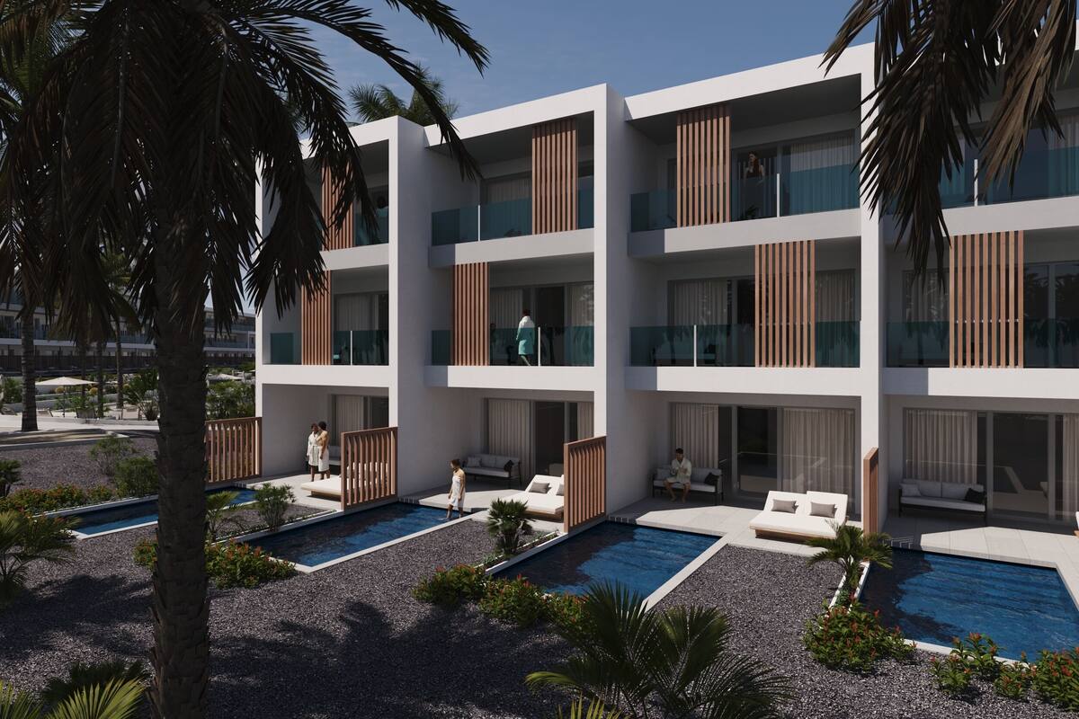 Un hotel modern amb balcons, piscines exteriors i palmeres.