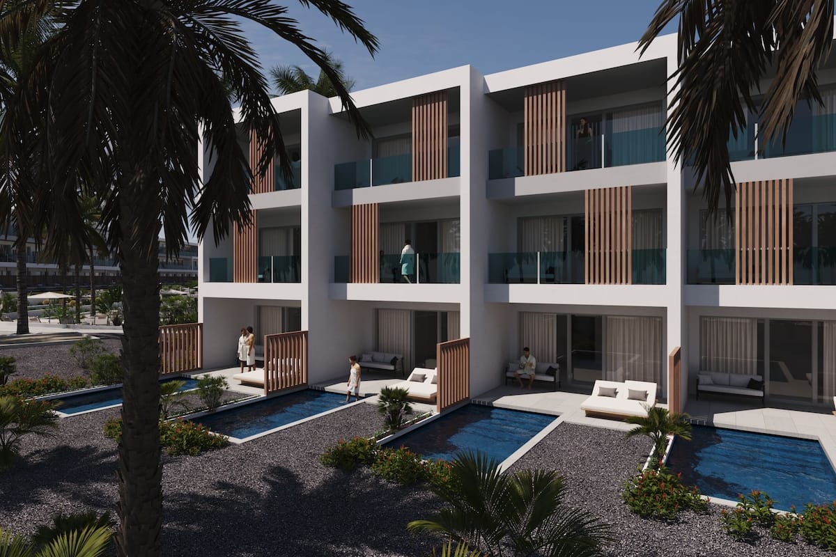A modern multi-story hotel with balconies, outdoor pools, and palm trees.