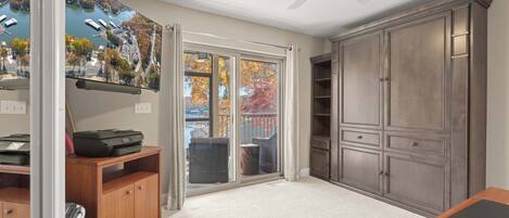 A room with a large sliding glass door leading to a balcony, a ceiling fan, and a large wardrobe.