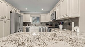 Una cocina moderna con gabinetes blancos, electrodomésticos de acero inoxidable y encimera de granito.
