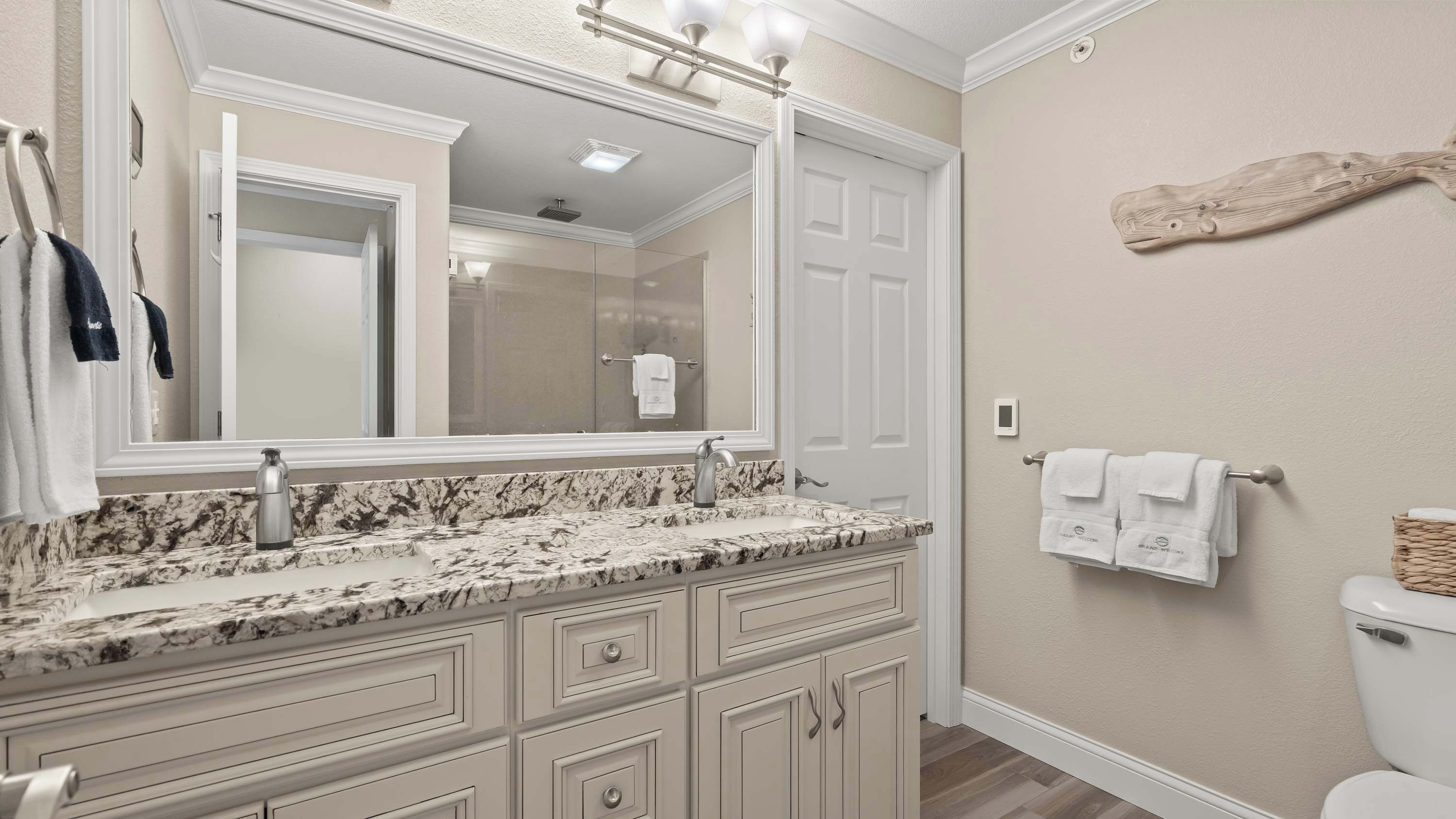 A bathroom with a marble vanity, a large mirror, a towel rack, and a toilet.