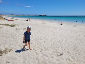 Una playa arenosa con gente y un cielo azul despejado.