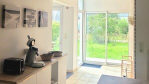 Una cucina moderna con zona pranzo, un tostapane, un bollitore e un'ampia finestra che si affaccia su un giardino.