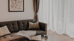 Ein modernes Wohnzimmer mit einem dunkelbraunen Sofa, einem weißen Couchtisch und einem gerahmten Kunstwerk an der Wand.
