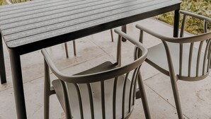 Eine Außenpatio mit Tisch und Stühlen, umgeben von Grünflächen und Wohnhäusern.