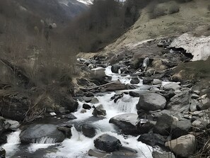 A rocky stream with flowing water, surrounded by natural terrain and vegetation.