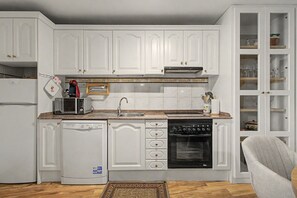 Cocina compacta con muebles blancos, horno integrado, lavavajillas y microondas.