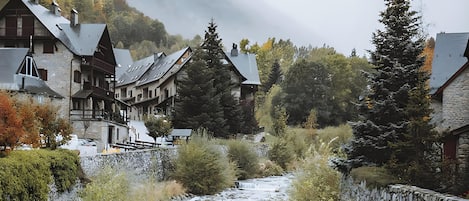 Ein Fluss fließt durch ein Dorf mit Steinmauern und traditionellen Gebäuden.
