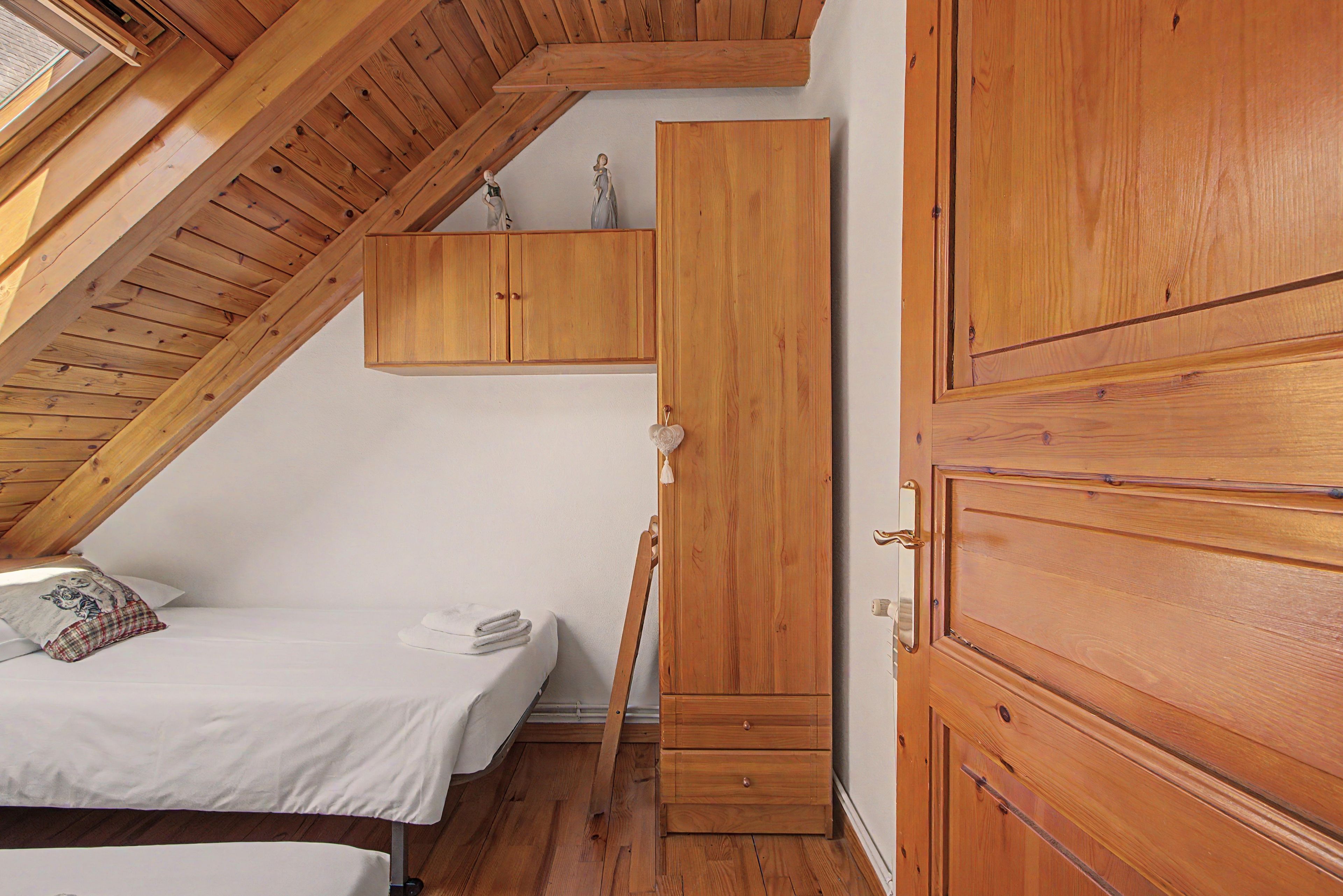 Une chambre avec un espace nuit en mezzanine, des meubles en bois et une fenêtre.