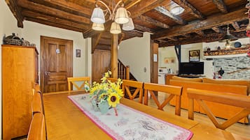 Un espace repas avec des meubles en bois, un lustre et une table agrémentée d’un centre de table floral.