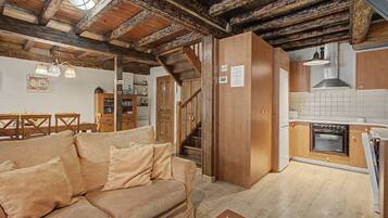 Un interior acogedor con una escalera de madera, una zona de cocina y un espacio de estar con sofá.