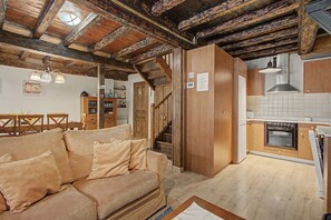 Un intérieur chaleureux avec un escalier en bois, un coin cuisine et un espace de vie doté d’un canap é.
