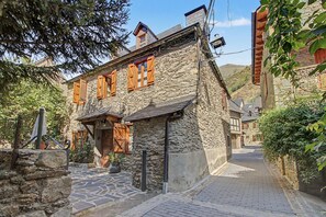 Un bâtiment en pierre avec des volets en bois, un escalier en pierre et un chemin pavé.