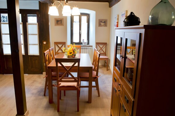A dining area with a wooden table and chairs, a vase with flowers, and a cabinet with drawers.