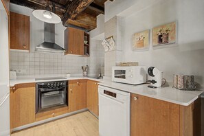 Une cuisine avec des meubles de rangement en bois, un four encastré, un four à micro-ondes et une machine à café.