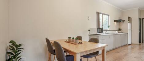 A modern kitchen with a dining table, chairs, and a potted plant.