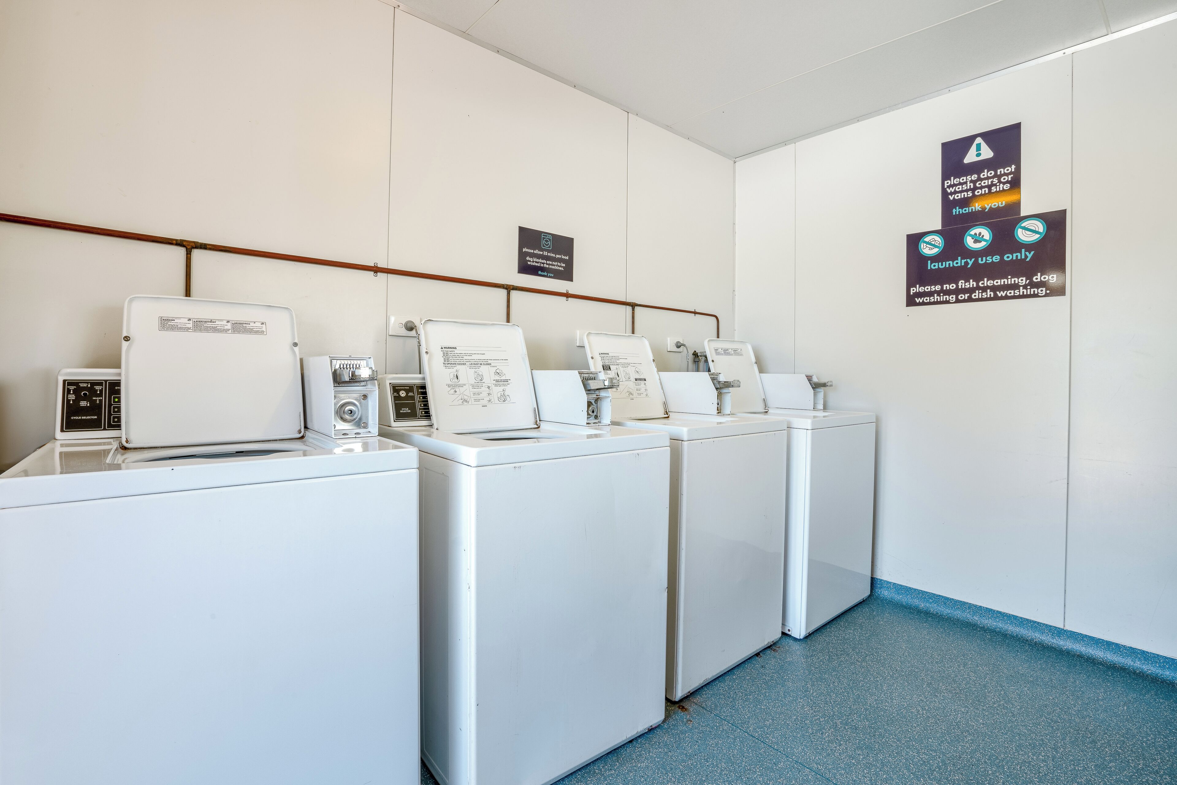 A laundry area with four washing machines and a sign indicating laundry use only.