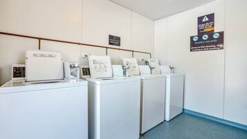 A laundry area with four washing machines and a sign indicating laundry use only.