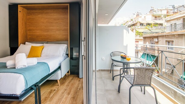 Una camera da letto moderna con un letto, un tavolino e un balcone con vista sulla città.