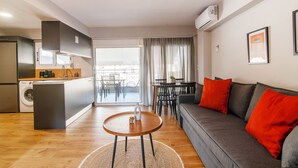 Un appartamento moderno con cucina, zona pranzo e soggiorno. Dispone di un divano, un tavolino da caffè e un tavolo da pranzo con sedie.
