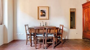 A dining area with a wooden table and chairs, a framed picture on the wall, and a wooden cabinet. - Apartment in the Historic Center of Pietrasanta (Pietrasanta)