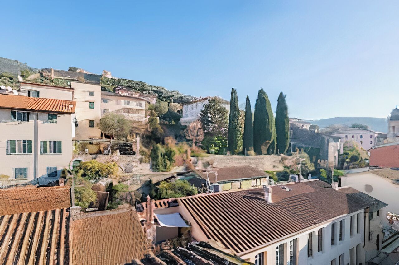 Un quartier résidentiel avec des maisons à étages, une colline couverte de végétation et un ciel dégagé.