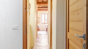 A hallway with a stone-tiled floor, a wooden door on the right, and a welcome mat at the entrance. - Apartment in the Historic Center of Pietrasanta (Pietrasanta)