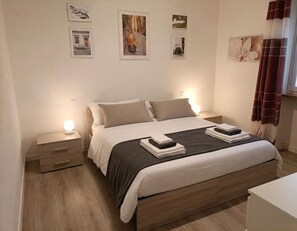 A bedroom with a bed, bedside tables, and wall art.