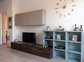 Un salon moderne avec un téléviseur, une bibliothèque et une horloge murale.