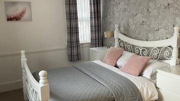 Un dormitorio con cama, mesita de noche y pared decorada con un diseño de pájaros.