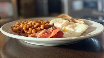 A plate of food with beans, bacon, ham, eggs, and toast.