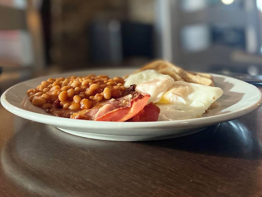 A plate of food with beans, bacon, ham, eggs, and toast.