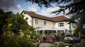 A two-story building with a flat roof and a covered outdoor area with a glass roof. - Hunters Meet Ltd  (Hatfield Heath)