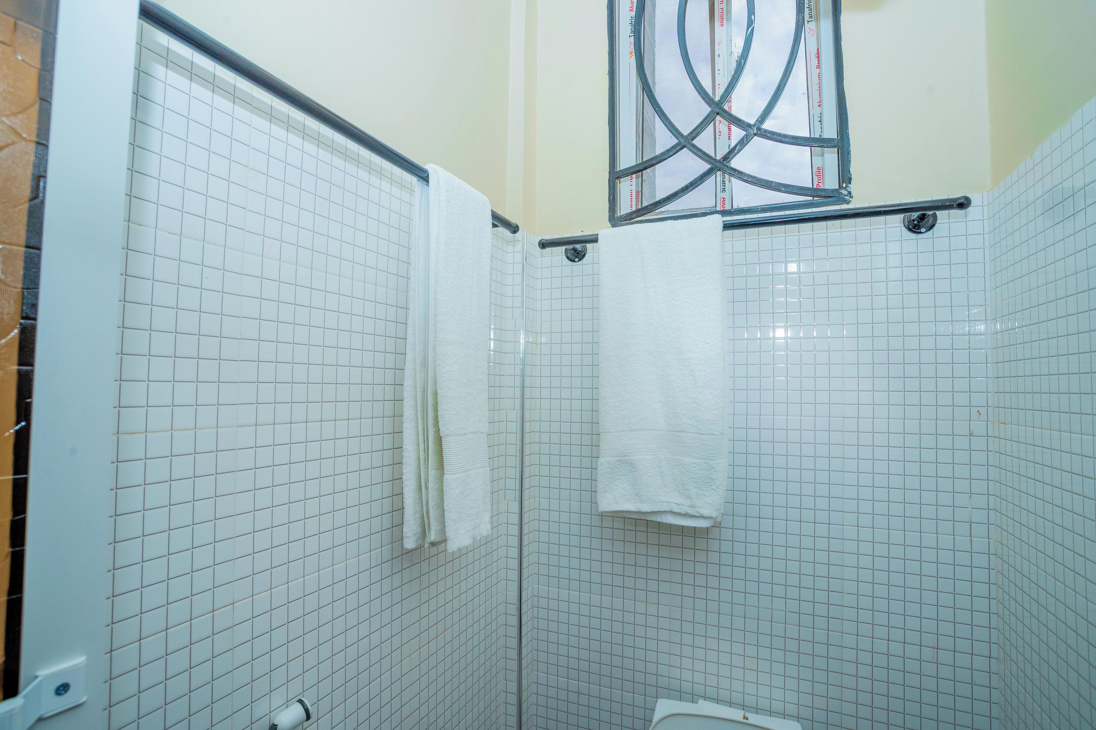 A tiled bathroom with a shower, a toilet, and a towel rack.