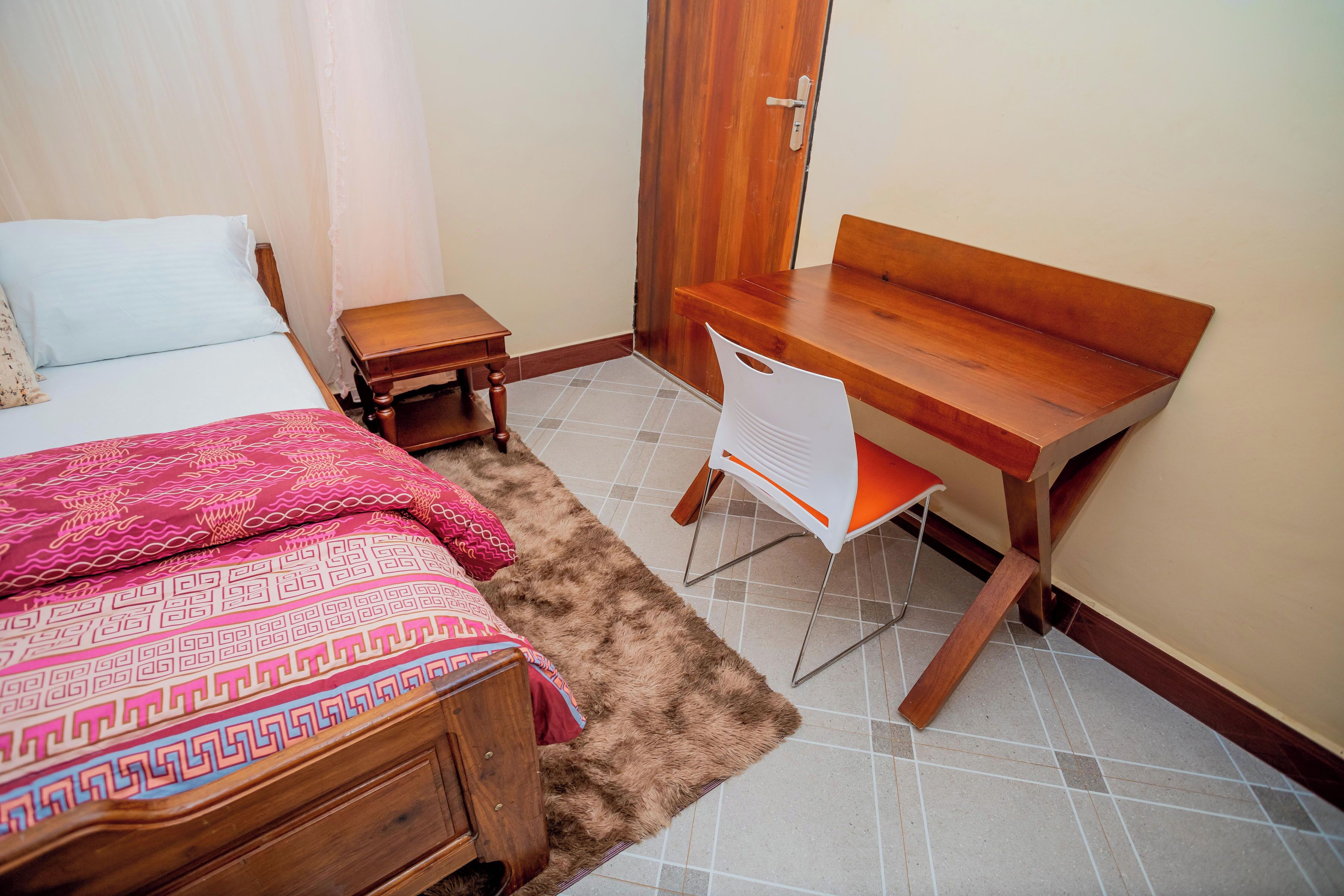 Une chambre à coucher avec un lit, un bureau en bois, une chaise et une petite table.