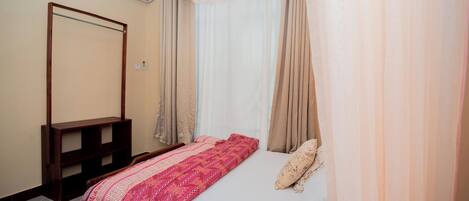 Une chambre à coucher avec un lit, une tête de lit en bois, une table de chevet et un miroir.