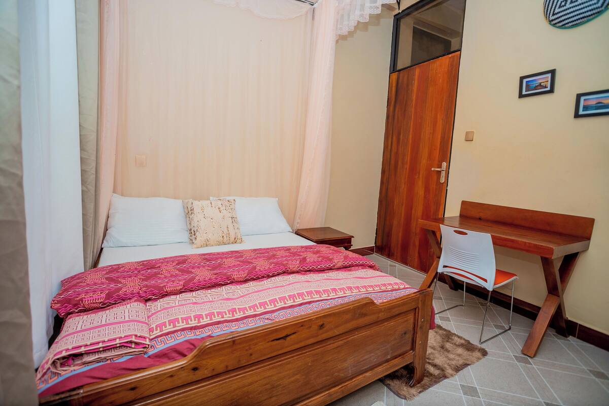 A bedroom with a wooden bed, a desk, and a chair.