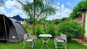 A tent set up on a grassy lawn with a table and four chairs. - Volunteer Hostel (Moshi)