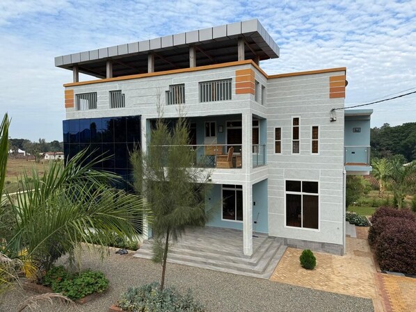 Una casa moderna de dos pisos con techo plano, ventanas grandes y un espacio exterior cubierto.