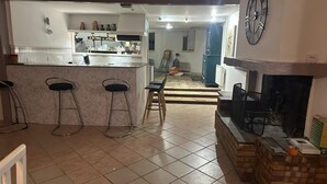 Une cuisine dotée d’un îlot central, de deux tabourets de bar, d’une cheminée et d’une horloge murale.