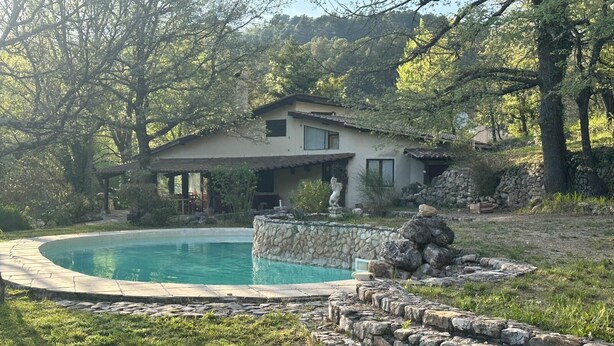 Une maison avec une piscine, entourée de murs en pierre et dotée d’un chemin en pierre.