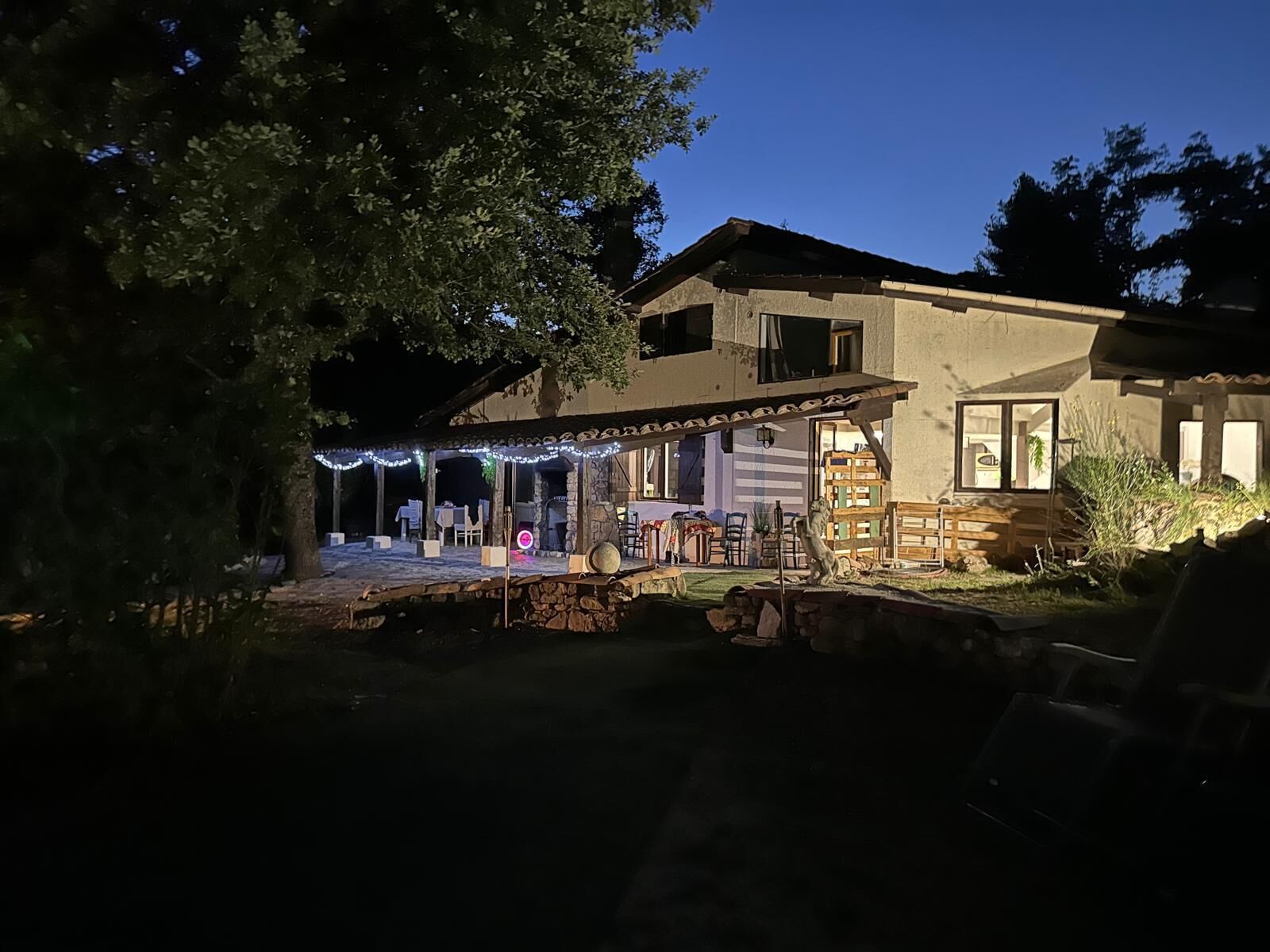 Une maison à deux étages dotée d’un patio, d’un espace salon extérieur et d’une cheminée en pierre.