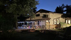 Une maison à deux étages dotée d’un patio, d’un espace salon extérieur et d’une cheminée en pierre.