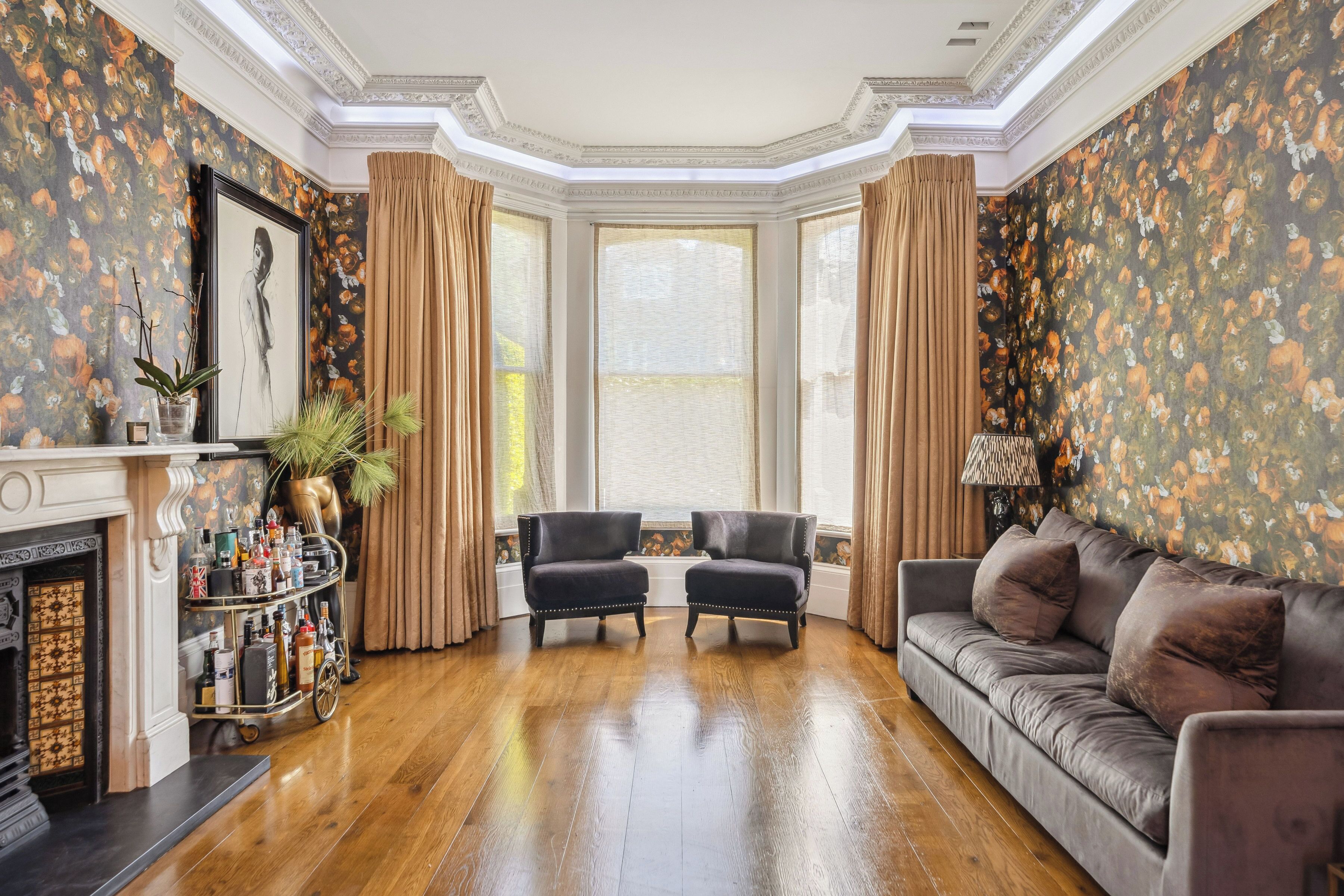 A room with a fireplace, two armchairs, a sofa, and a window with curtains.