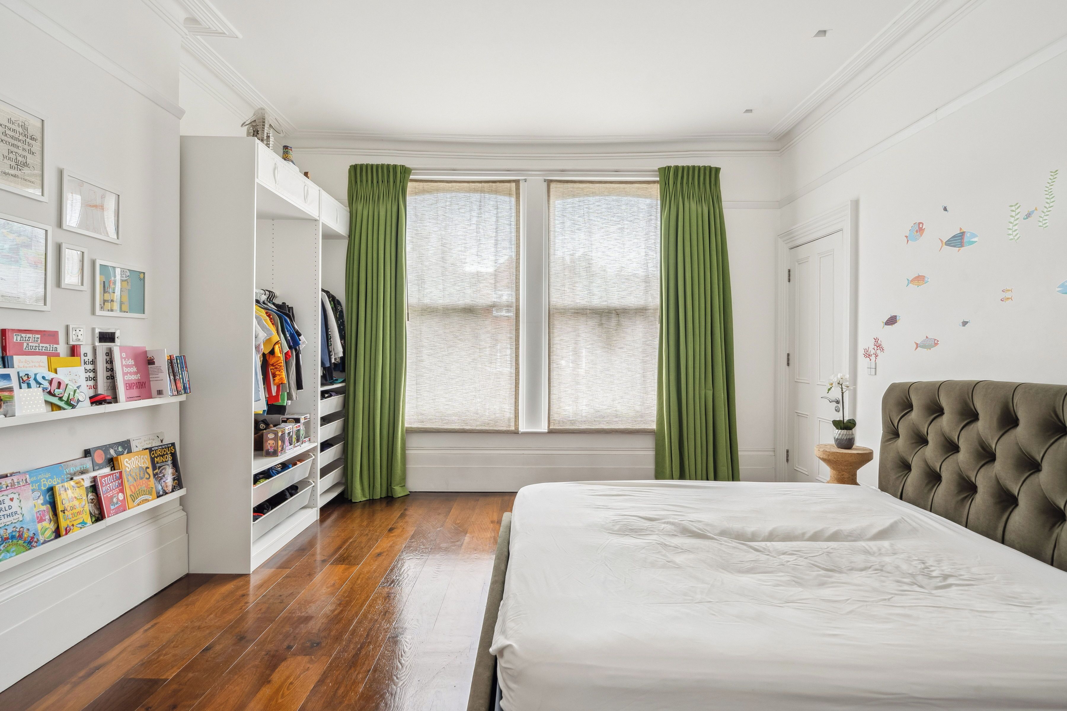 Un dormitorio con cama, armario y ventana con cortinas.