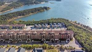 Un hotel de varios pisos con estacionamiento y vistas a un lago y un bosque circundante.