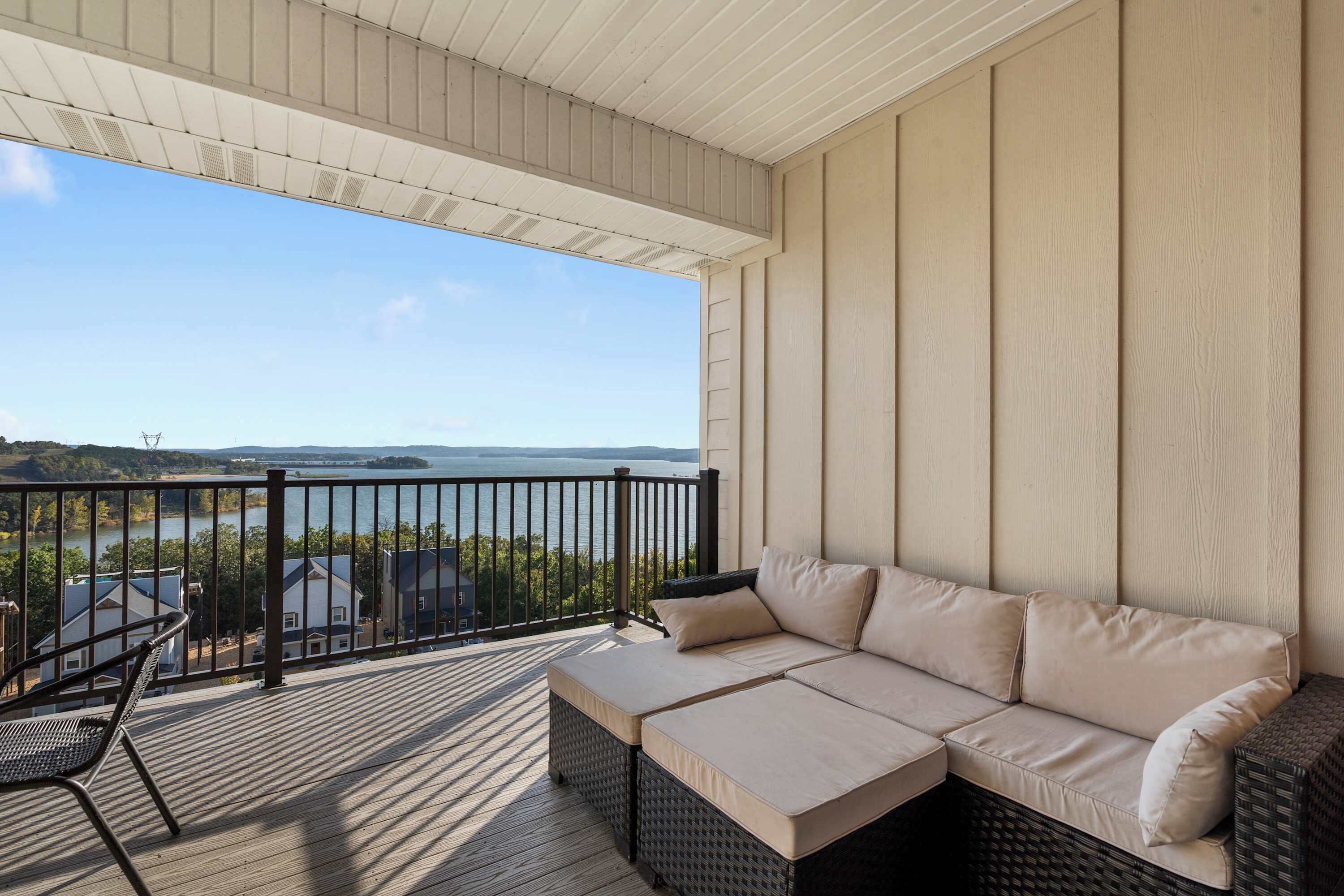 Ein Balkon mit einem Korbsessel und einem Stuhl, der auf ein Gewässer und Gebäude blickt.