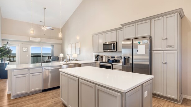 Una cocina moderna con una isla central, electrodomésticos de acero inoxidable y armarios de color gris claro.