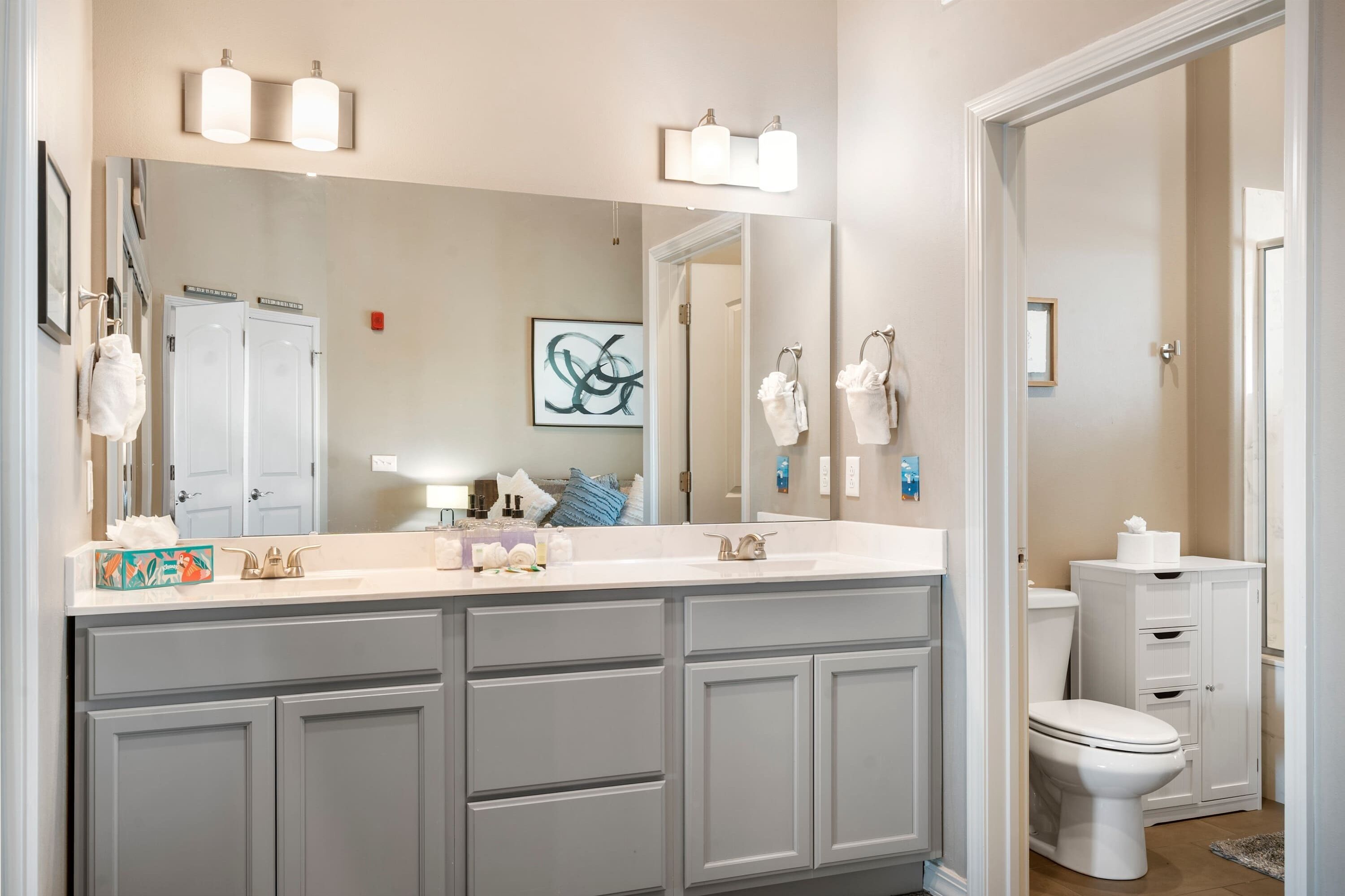 A modern bathroom with a large vanity, double sinks, and a toilet.