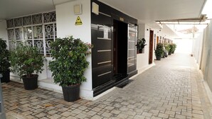 A hotel corridor with potted plants, a reception area, and a tiled floor. - Aaru Residency (Coimbatore)